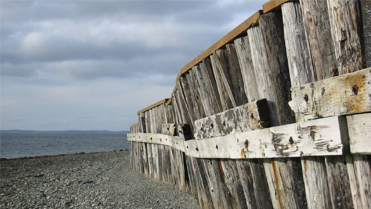 Old wooden bulkhead on a beach with a view of the water
